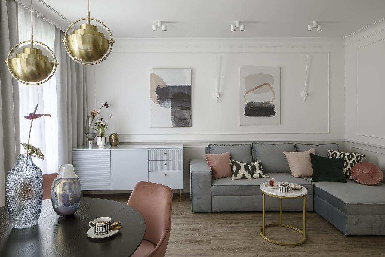 Elegancki salon z szarą sofą i złotymi akcentami.