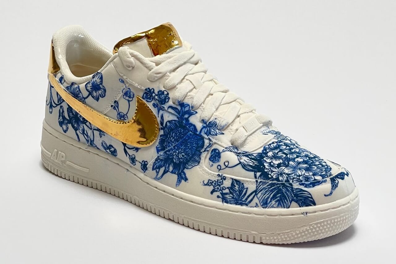 Białe sneakersy z niebieskimi wzorami i złotymi detalami. Styl pełną parą!