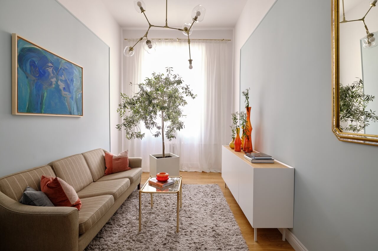 Przytulny salon z roślinami, nowoczesnym obrazem i designerską sofą.