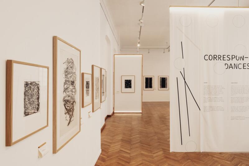 Wystawa sztuki w minimalistycznej galerii z drewnianą podłogą.
