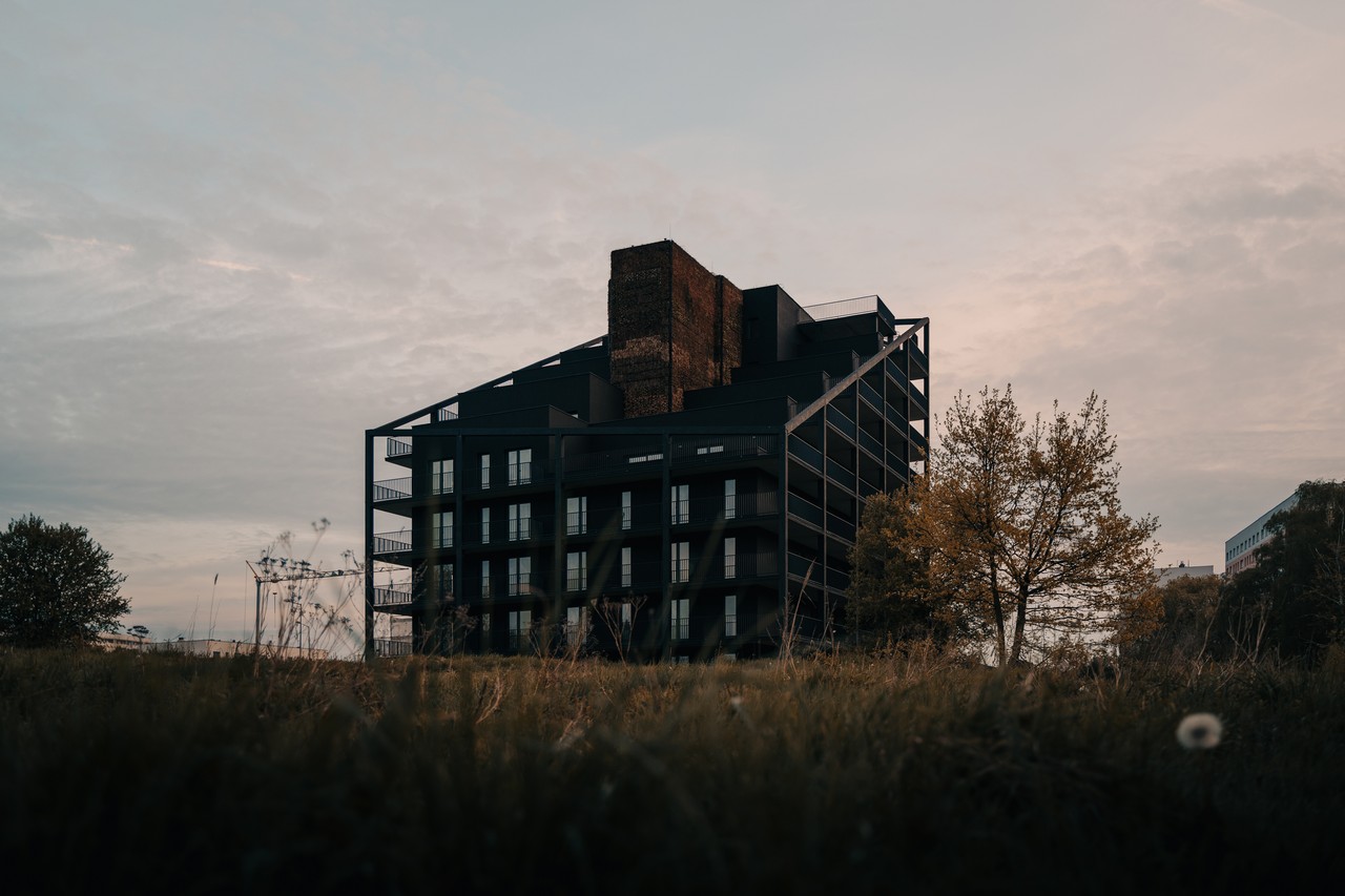 Ciemny budynek z nowoczesną architekturą w otoczeniu drzew.