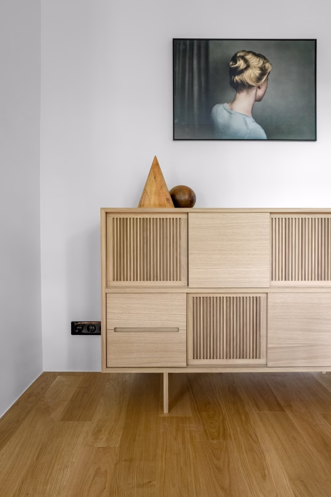 Jasna komoda z dekoracyjną sztuką na ścianie, minimalizm i elegancja.