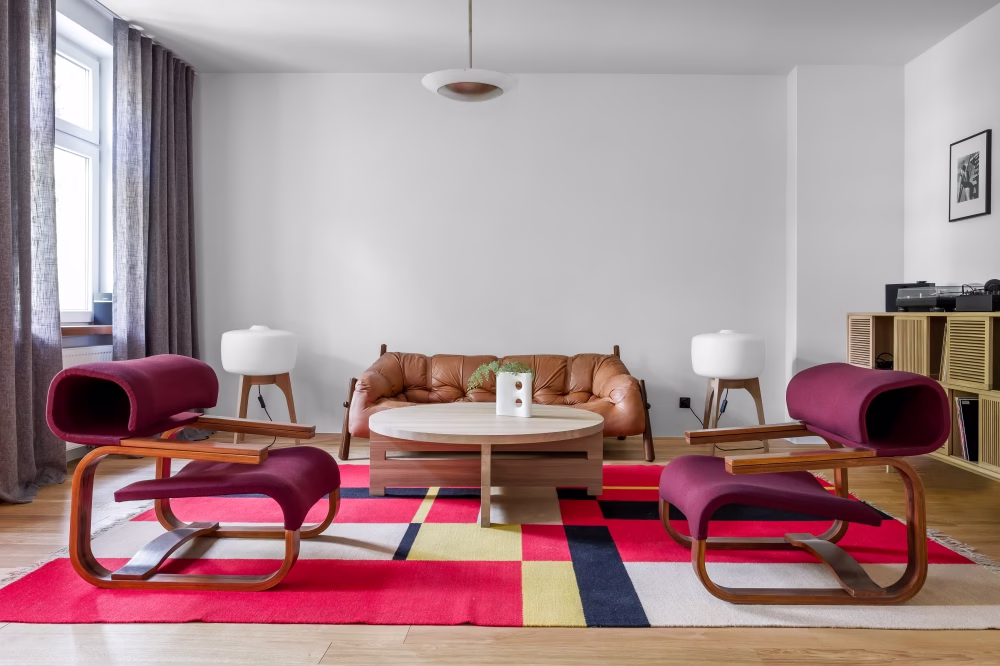 Stylowy salon z designerskimi fotelami i kolorowym dywanem.