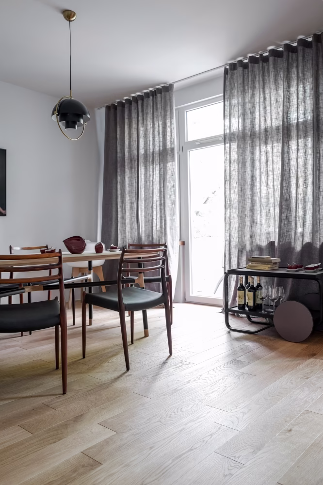 Stylowe wnętrze: drewniana podłoga, nowoczesne krzesła, eleganckie zasłony.