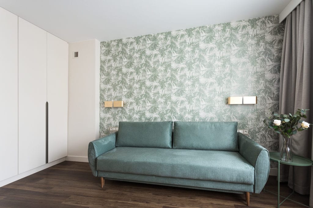 Zielona sofa i zielona tapeta w apartamencie w Kielcach