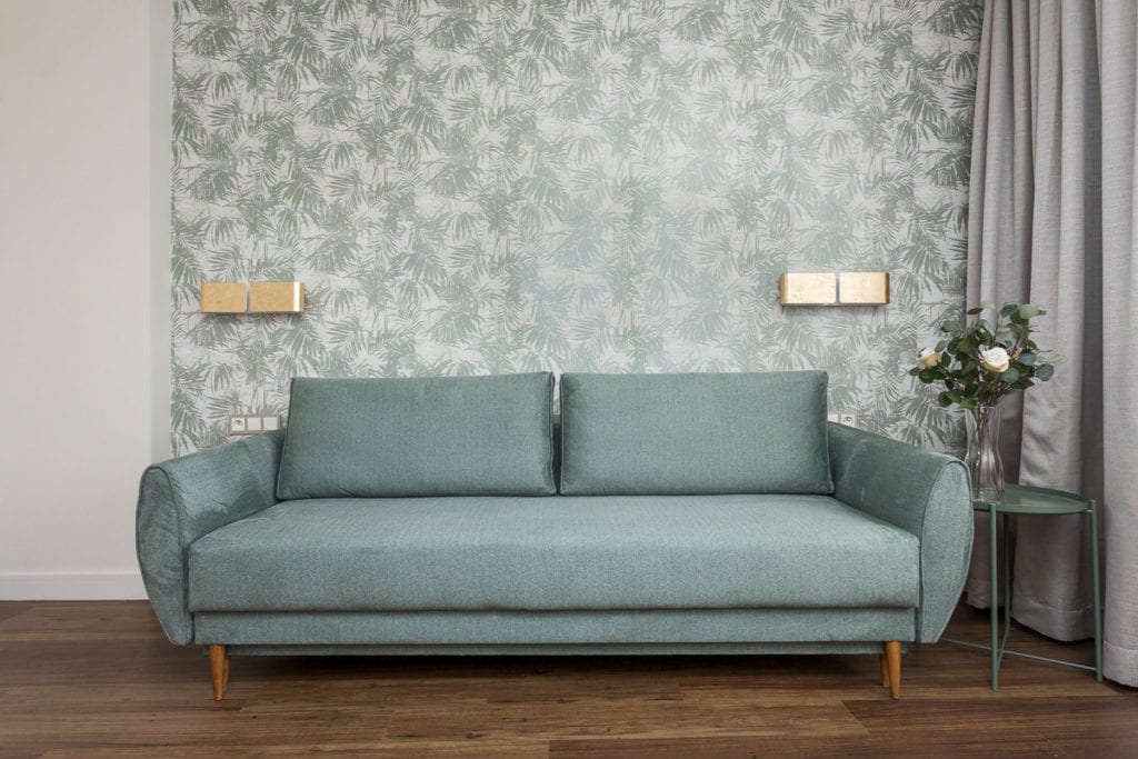 Zielona sofa i zielona tapeta w mieszkaniu zaprojektowanym przez Clou Design