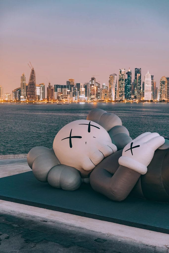 KAWS - Brian Donnelly i instalacja artystyczna na tle panoramy miasta Doha