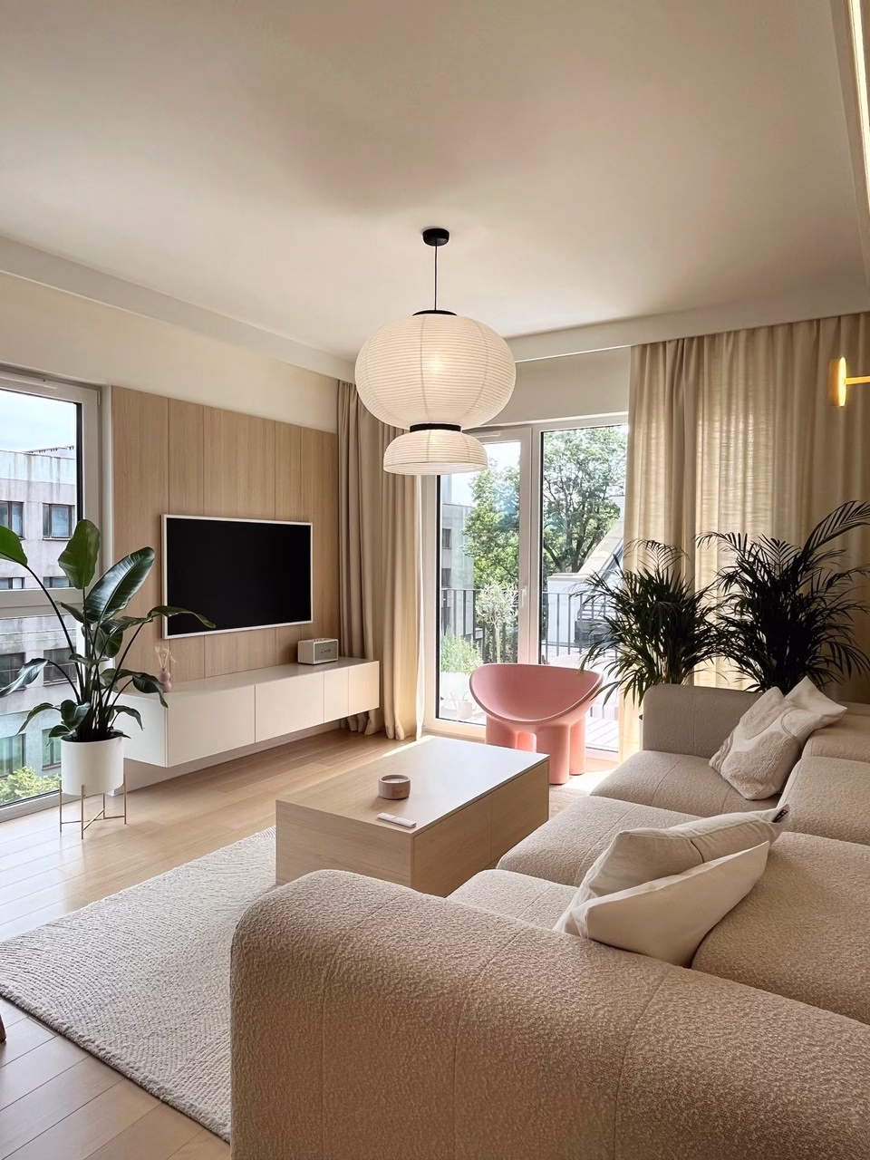 Uporządkowany salon z designerskimi meblami i zielenią.