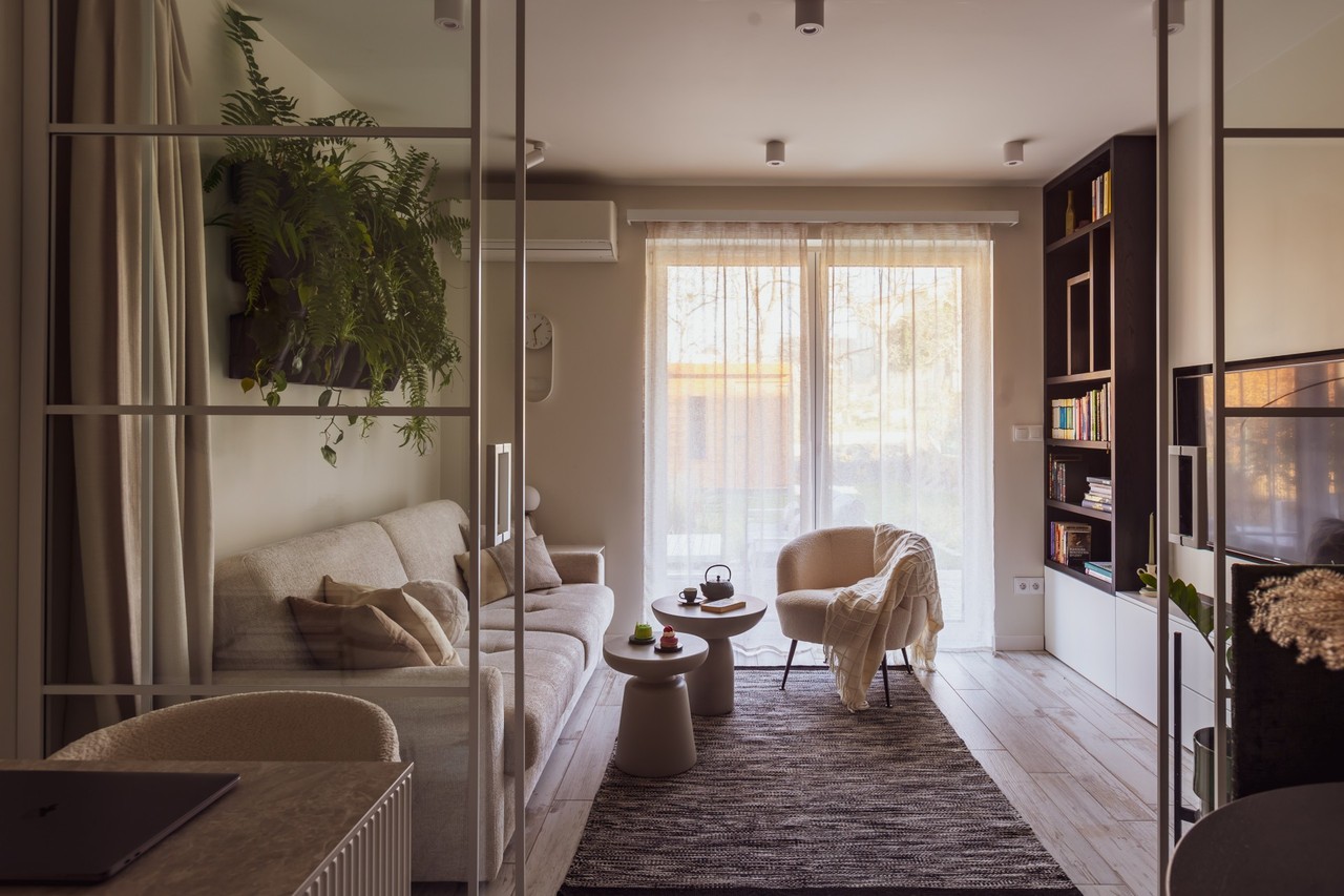 Cosy living room with sofa, armchairs, greenery and wooden floor.
