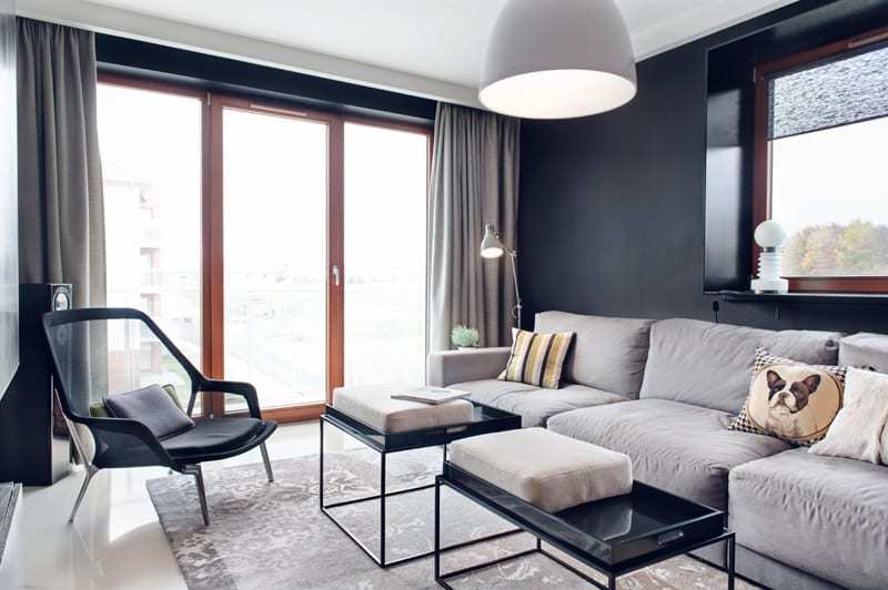 Salon z dużym oknem i szarą ścianąw apartamencie projektu pracowni formativ