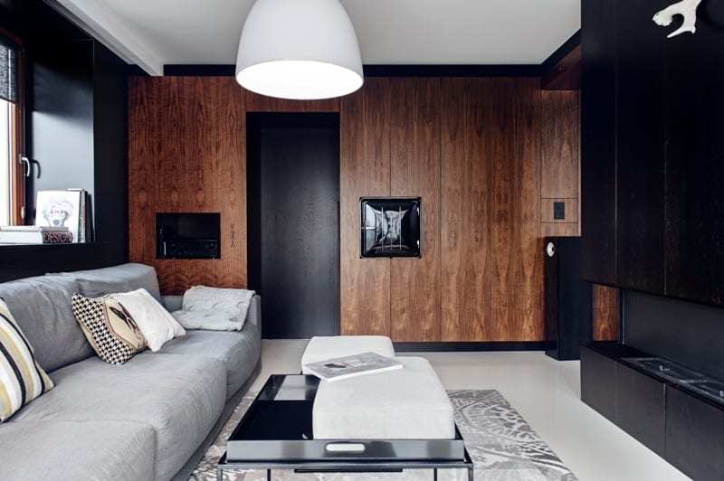 Salon z brązową ścianą i czarnymi drzwiamiw apartamencie projektu pracowni formativ
