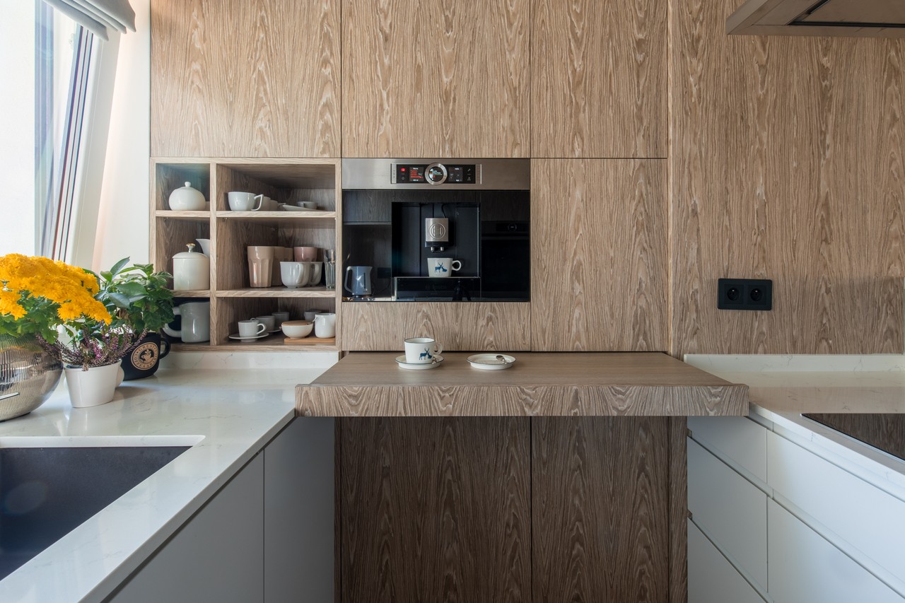 Wooden kitchen with modern coffee machine and white worktop.