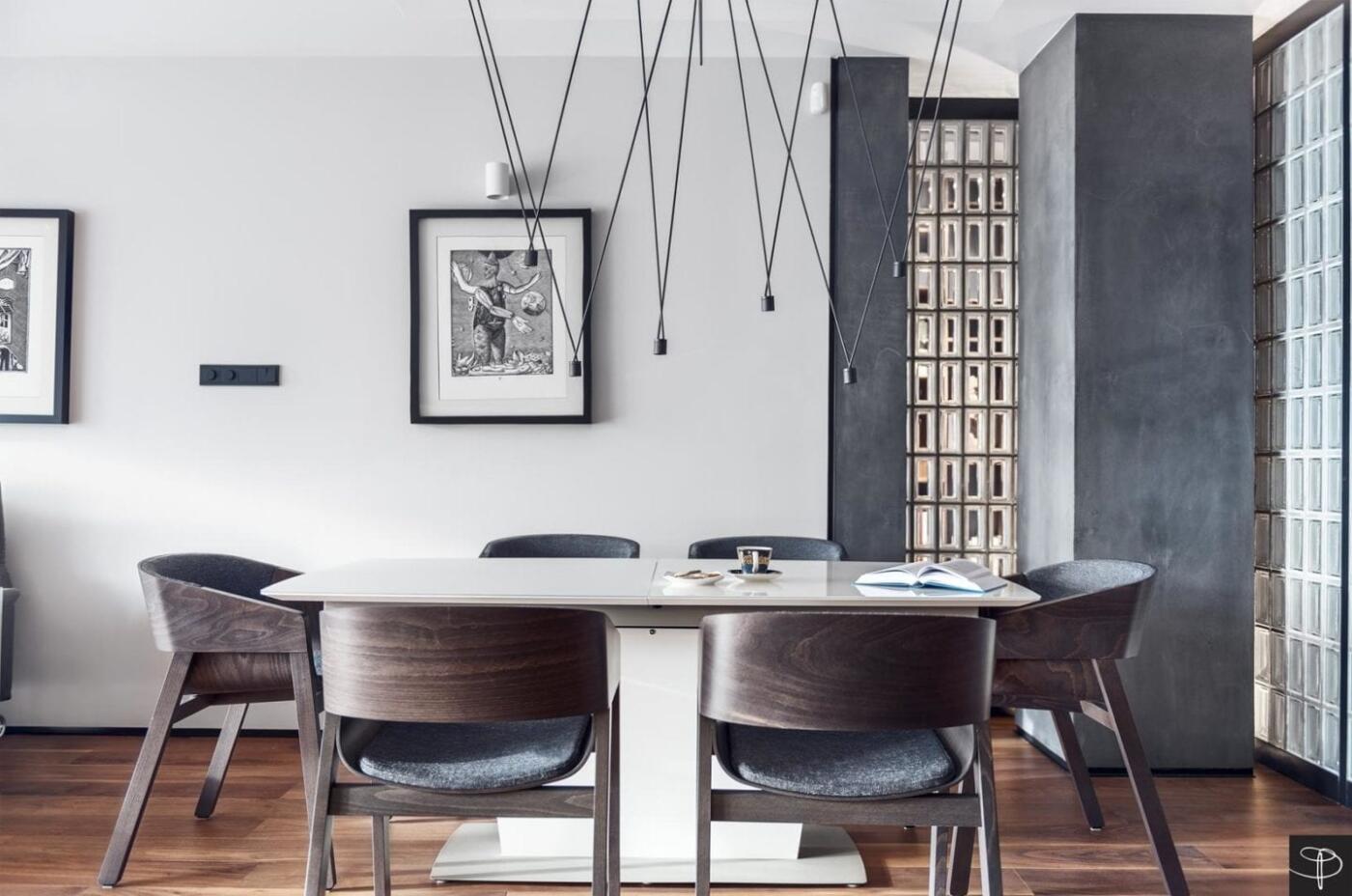 Nowoczesna jadalnia z designerskimi krzesłami i sztuką na ścianach.