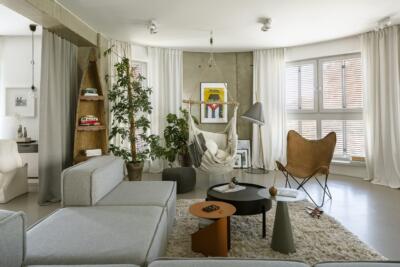 Nowoczesny salon z wiszącym fotelem i designerskimi stolikami.
