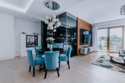 Nowoczesny salon z niebieskimi krzesłami i designerskim oświetleniem.
