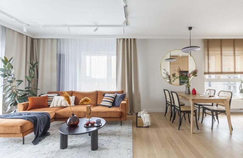 Nowoczesny salon z dużą sofą i eleganckim stołem jadalnym.