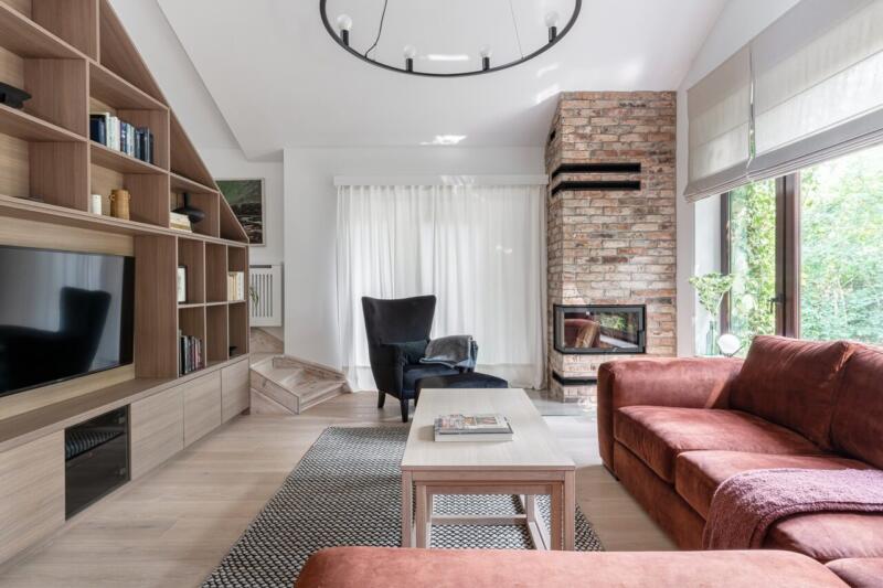 Nowoczesny salon z ceglaną ścianą i eleganckim kominkiem.