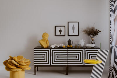 Awangardowy salon z geometryczną szafką i żółtą rzeźbą.