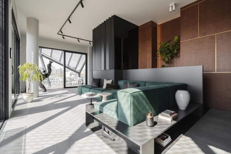 Nowoczesny salon z zieloną sofą i dużymi oknami.