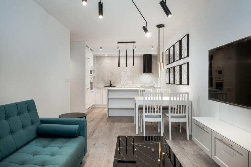 Nowoczesny salon z kuchnią, industrialne oświetlenie, elegancki wystrój.