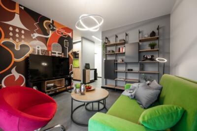 Nowoczesny salon z barwną ścianą i designerskimi meblami.