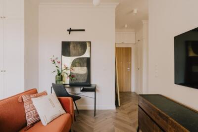 Stylowy salon z pomarańczową sofą i nowoczesną sztuką.