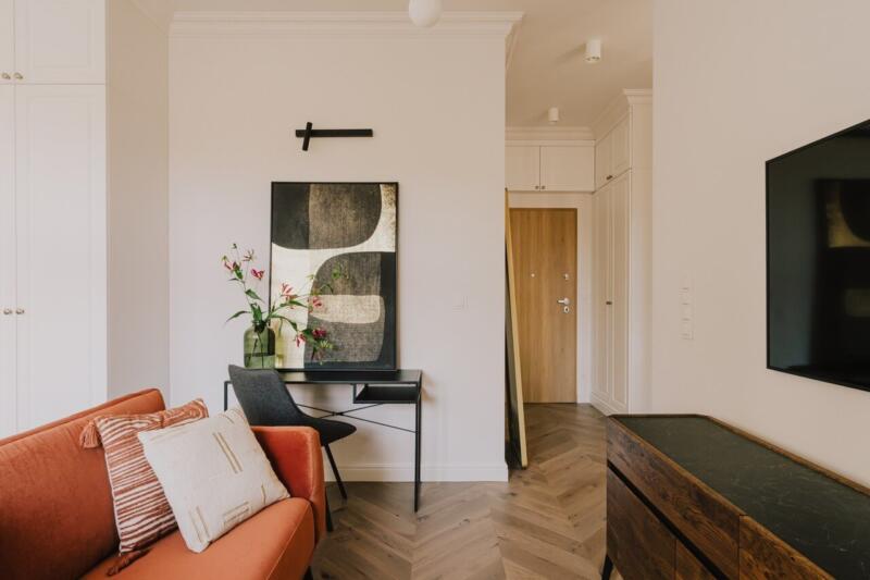 Stylowy salon z pomarańczową sofą i nowoczesną sztuką.