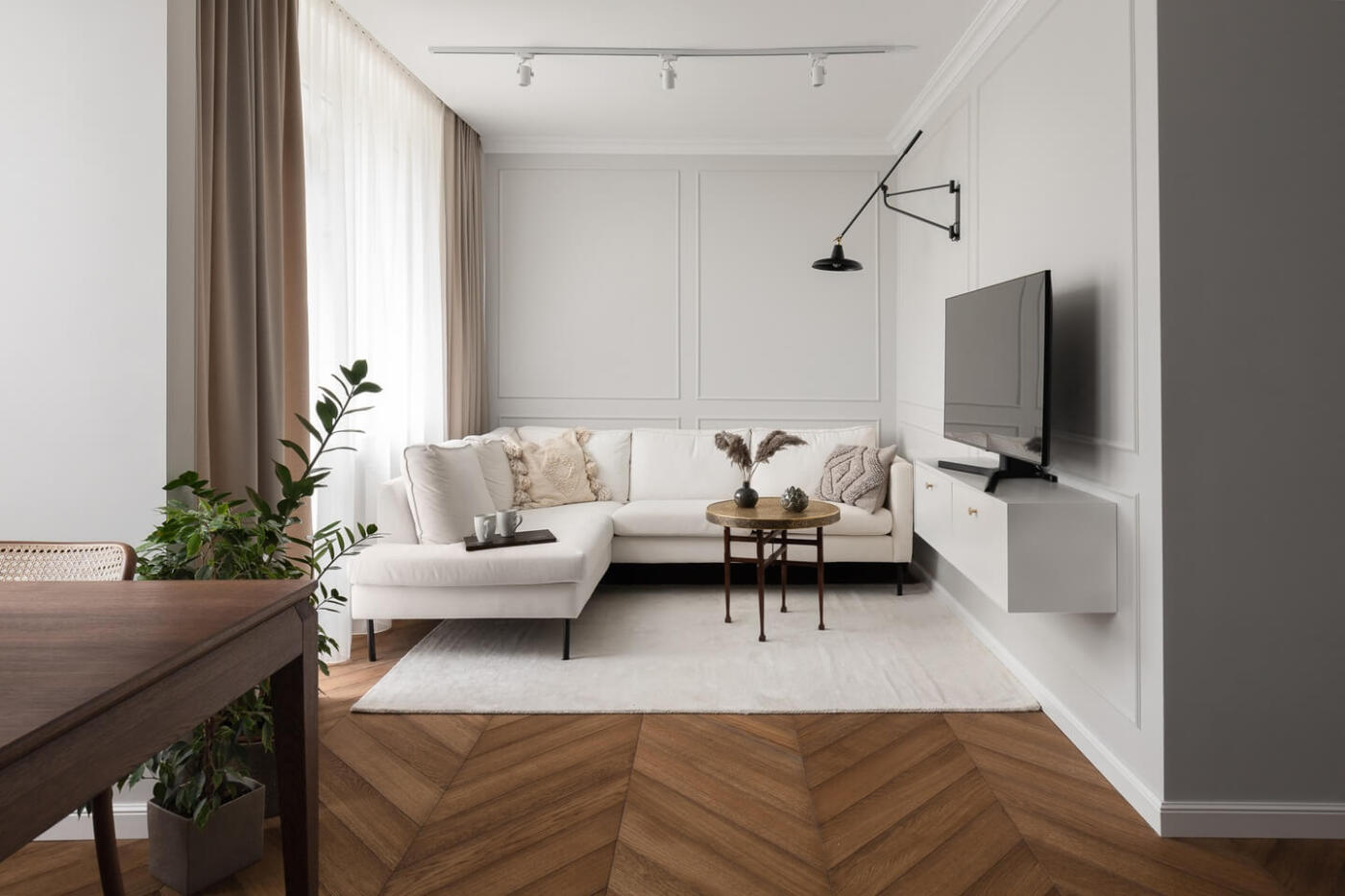 Nowoczesny salon z białą sofą i designerskim oświetleniem ściennym.
