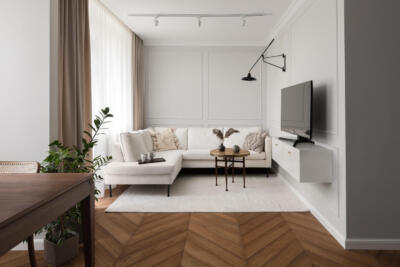 Nowoczesny salon z białą sofą i designerskim oświetleniem ściennym.