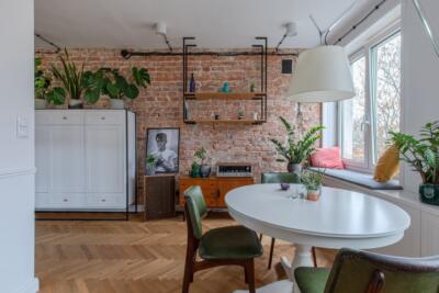 Loftowe wnętrze z ceglaną ścianą, zielone rośliny i vintage meble. Pięknie, prawda?