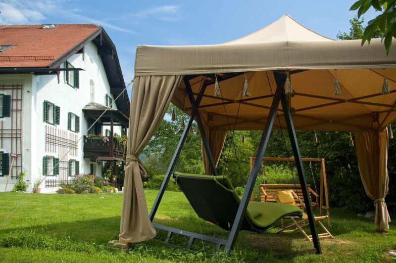 Oaza relaksu w ogrodzie z nowoczesnym zadaszeniem i huśtawką. Idealne miejsce na chwilę wytchnienia!