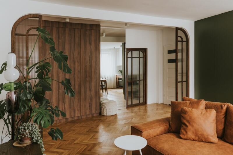 Nowoczesny salon z drewnianymi drzwiami i stylową sofą.