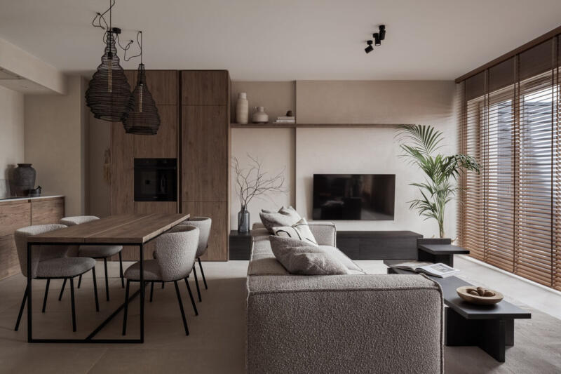 Salon w stylu minimalistycznym z drewnianymi akcentami i rośliną.