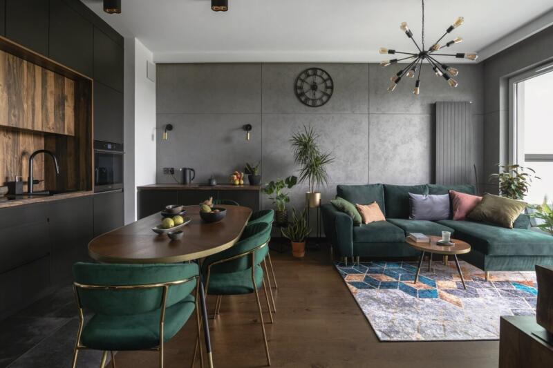 Nowoczesny salon z zieloną sofą i designerskim oświetleniem.