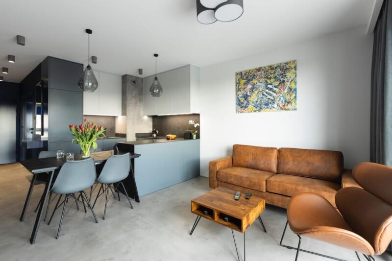 Współczesny salon z designerską kuchnią i skórzaną sofą.