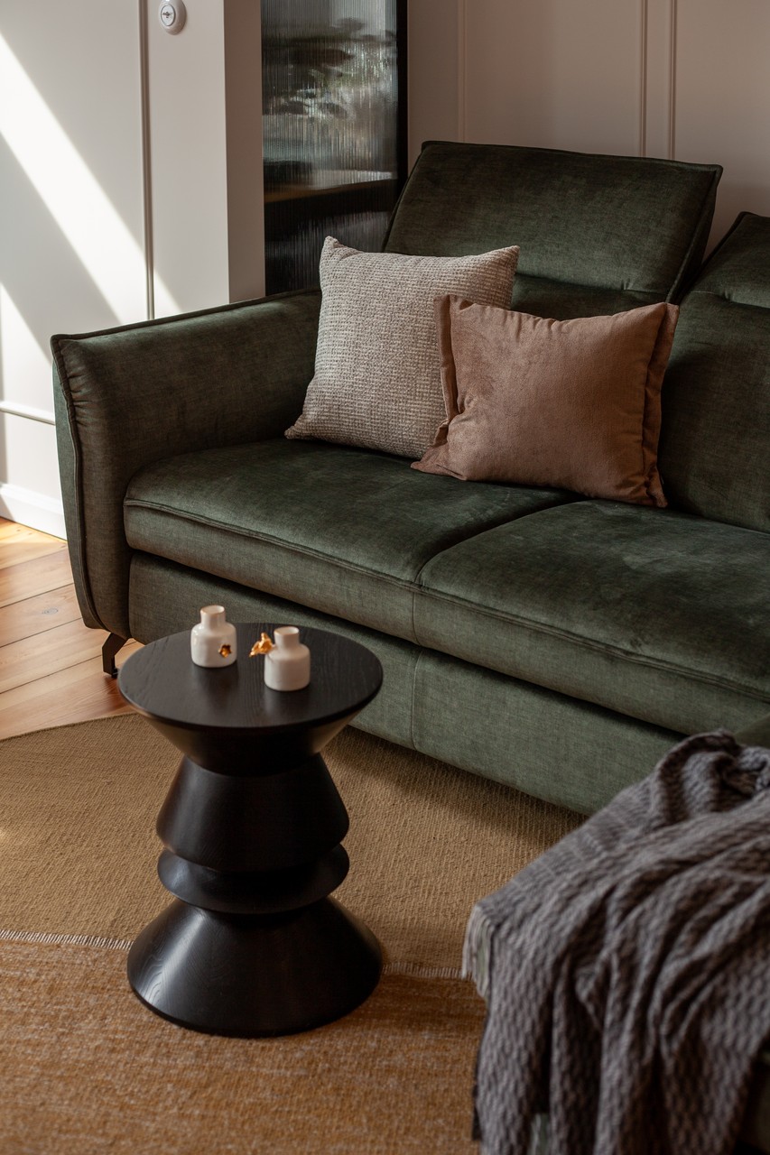 Zielona sofa z poduszkami, stylowy stolik w salonie.