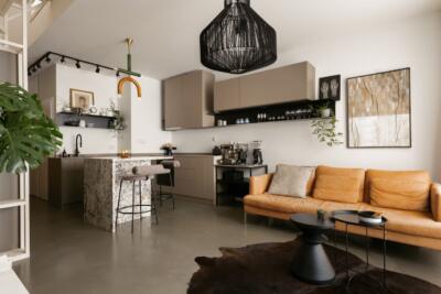 Nowoczesny salon z kuchnią, skórzana sofa i stylowe oświetlenie.