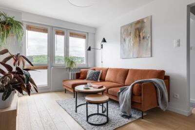 Stylowa sofa w ciepłym salonie z roślinami i nowoczesnym obrazem.