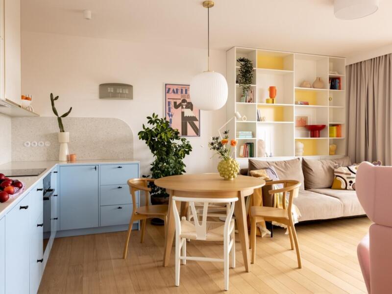 Przestronny salon z pastelową kuchnią i designerskimi dodatkami.