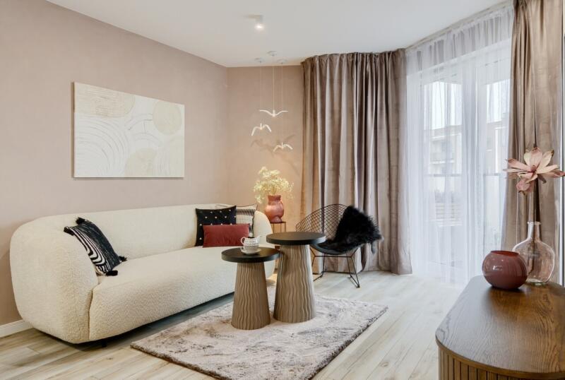 Salon z kremową sofą, designerskimi stolikami i nowoczesnym wystrojem.