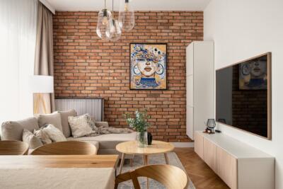 Nowoczesny salon z ceglaną ścianą i designerskimi dodatkami.