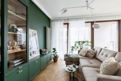Nowoczesny salon z zielonymi akcentami i wygodną sofą.