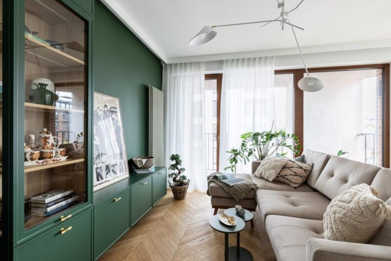 Nowoczesny salon z zielonymi akcentami i wygodną sofą.