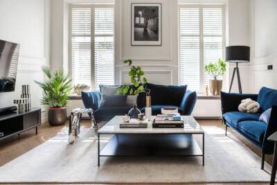 Elegancki salon z granatową sofą i designerskim stolikiem.