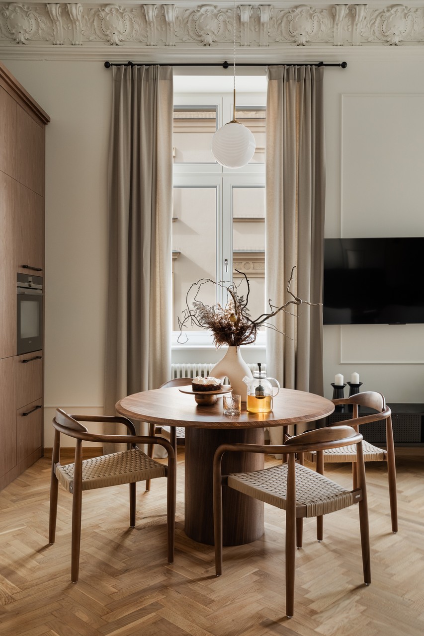 Elegancki salon z okrągłym stołem i drewnianymi krzesłami.