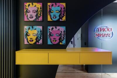 Wnętrze z pop-artowymi mozaikami i neonowym napisem.