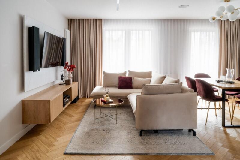 Elegancki salon z beżową sofą, drewnianą komodą i modernistycznymi akcentami.