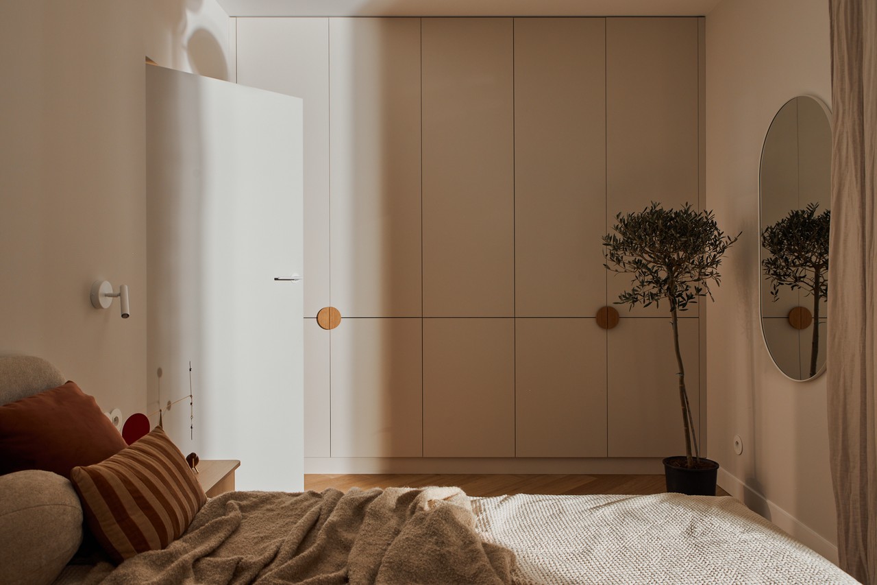 Minimalistyczna sypialnia z szafą wnękową i rośliną w donicy.
