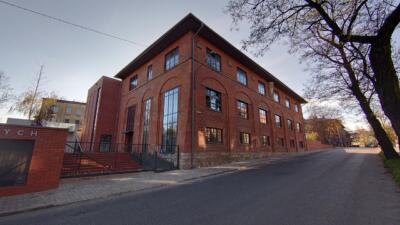 Ceglana architektura z wielkim przeszkleniem na rogu ulicy.
