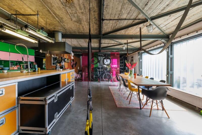 Loftowy salon z otwartą kuchnią, industrialne detale, stół jadalny.
